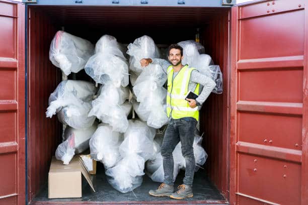 Portrait of male dock inspector with stock. Mid adult worker is standing in cargo container. He is wearing reflective clothing.